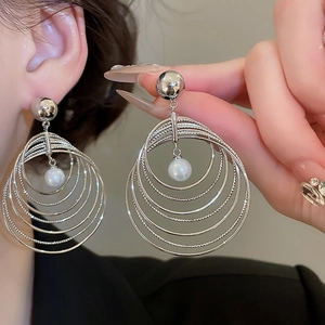 Detailed close-up of silver multilayer circular hoop earrings with elegant white pearls