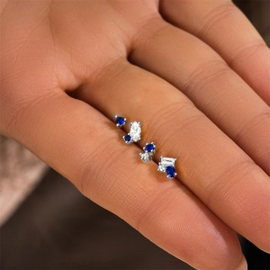 Close-up of S925 sterling silver earrings set with blue gems and clear zircon on a hand