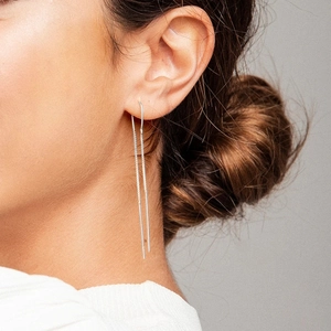 Detailed close-up of a long silver S925 sterling silver tassel earring on a model ear