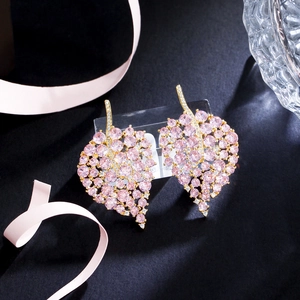 Elegant gold leaf earrings with pink zircon stones on a premium dark background