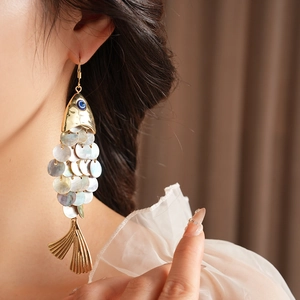 Detail of vintage fish earrings with iridescent shell scales and blue gemstone eyes