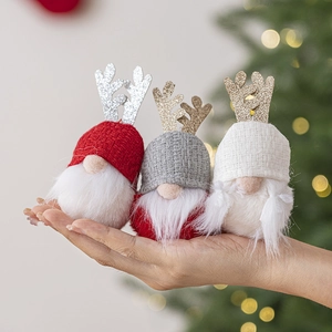 Three Christmas gnomes with sequined antlers and knitted hats held in hand for scale