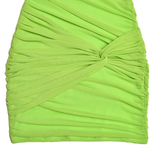 Détail d'une mini-jupe vert fluo en maille plissée avec un nœud stylé sur le devant