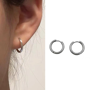 Detail of silver huggie earrings showing minimalist design and smooth metallic finish