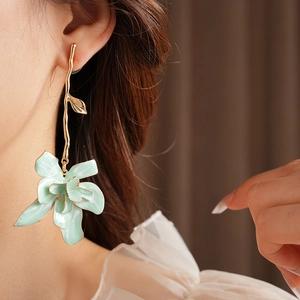 Close-up of vintage golden earrings featuring large light green enamel flower petals