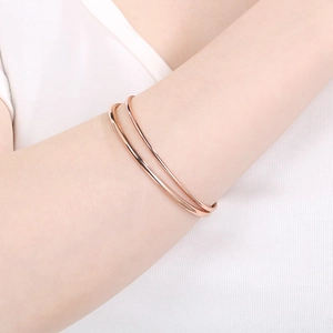 Close-up of elegant rose gold double-layered open bangle on woman's wrist