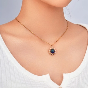 Close-up of golden sun pendant with deep blue gemstone and sparkling crystals on model