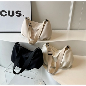 Three minimalist nylon crossbody bags in black and beige displayed on white steps