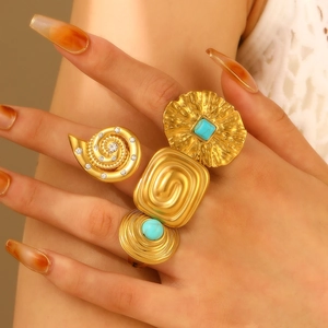 Detailed view of bohemian gold rings with turquoise stones and textured finishes