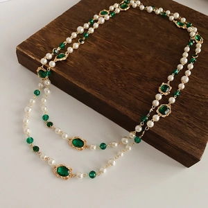 Detail of vintage multilayer pearl necklace featuring a green gemstone on golden chain