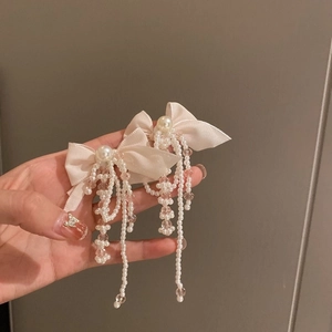 Detail of cream bow hair clip with large faux pearl and beaded tassel drop ornament