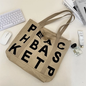 Macro shot of khaki canvas tote with black lettering on a modern office desk setup