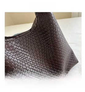 Detail of dark brown woven leather texture on a high-capacity retro shoulder tote bag