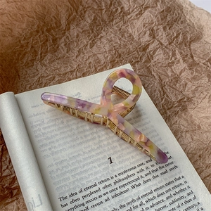 Detailed close-up of large acetate claw clip with amber texture on a vintage book
