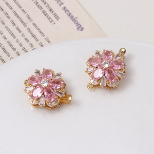 Close-up of golden flower clasps with pink crystals and zircon for pearl jewelry
