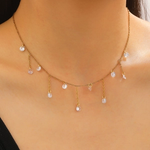Detail van gouden kwastjesketting met zirkoonhangers om de nek voor een elegante valling