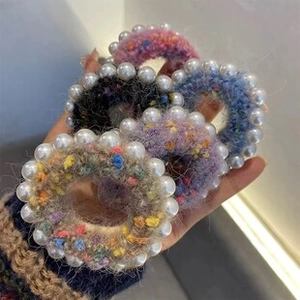 Close-up of four handmade knit hair ties with pearl beads in pink, blue, and purple