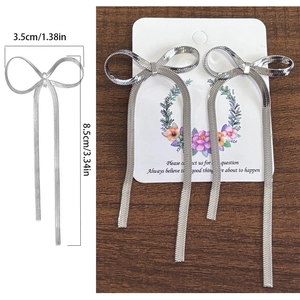 Detailed view of silver bow-knot tassel earrings with measurements in centimeters and inches