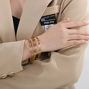 Close-up of minimalist 18K gold plated stackable stainless steel multi-layered bangle set
