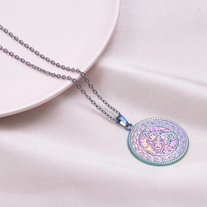 Macro shot of stainless steel necklace with iridescent celtic knot pendant on pink plate