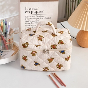 Close-up of beige quilted makeup bag with bear prints and silver metal double zippers