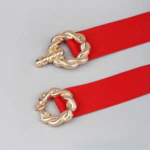 Detail of red elastic waist belt featuring a gold twisted metal buckle and textured strap
