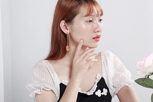 Détail de longues boucles d'oreilles dorées avec visage portées par un mannequin
