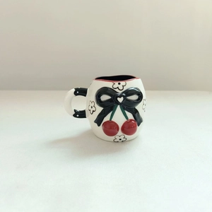 White ceramic cherry mug with 3D black bow and dotted handle on minimalist background