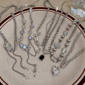 Detailed view of silver-toned Y2K necklaces with opal and moonstone accents in a ceramic tray