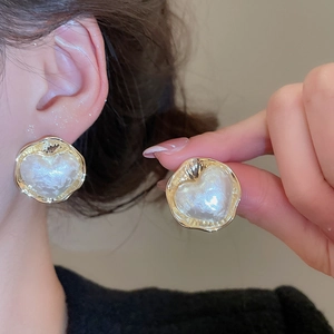 Dettaglio di un orecchino a cuore placcato oro 16K con trama di perle sull'orecchio
