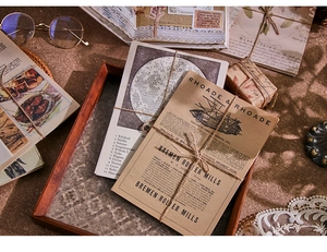 Close-up of vintage scrapbook paper with antique prints and twine on wooden tray