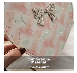 Close-up of pink heart-shaped PU leather bag with metallic silver bow detail