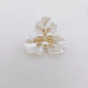 Detailed close-up of white pearlescent petals with central pearls and golden rhinestone stems