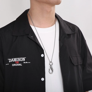 Close-up of stainless steel skull pendant with industrial hook clasp on male model