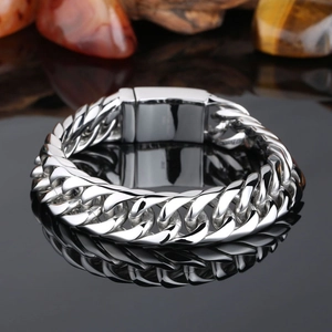 Polished silver cuban chain bracelet for men with rectangular clasp on black reflective surface