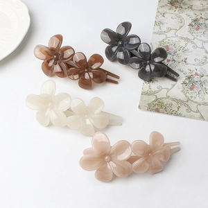 Flat lay of four vintage floral hair clips in brown, black, cream, and pink tones