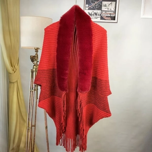 Close-up of red knit shawl with fluffy faux fur collar and long fringe tassel detail