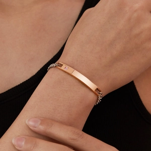 Minimalist stainless steel bracelet with gold bar and pink gemstone on a silver chain
