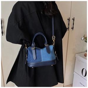 Dettaglio della borsa in patchwork di denim blu con manici in pelle e finiture dorate
