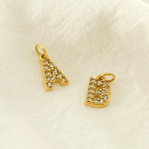 Detailed macro view of gold-plated alphabet A and B pendants with sparkling rhinestones