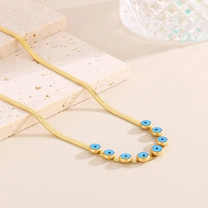 Close-up of golden flat snake chain necklace with blue evil eye charms on stone