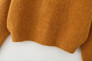 Close-up of mustard yellow knit sweater featuring ribbed hem and vertical texture