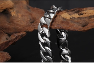 Macro detail of polished thick Cuban link chain wrapped on wood showing metallic texture
