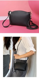 Detail of a black pebbled leather crossbody bag with silver hardware and white stitching