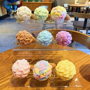 Colorful handmade crochet ice cream keychain set displayed on a clear tiered stand