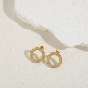 Detailed side view of gold-plated circular stud earrings with pavé-set crystals