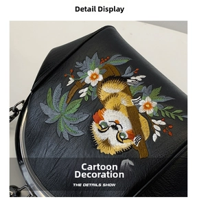 Close-up of black leather bag with colorful cartoon animal and floral embroidery detail