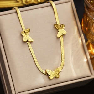 Detailed macro of 18k gold plated flat snake chain with three delicate butterfly pendants
