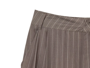 Détail du pantalon à rayures montrant les passants de ceinture et les plis sur le devant