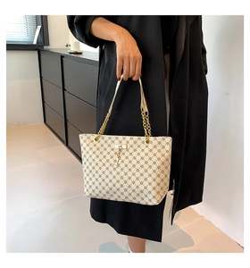 Dettaglio della borsa tote bianca con stampa floreale, catena dorata e ciondolo a cervo su cappotto